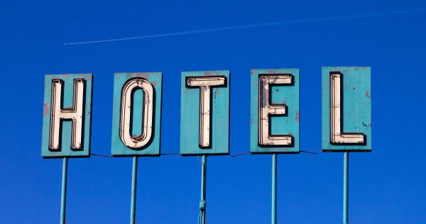 Grungy Old Hotel Sign And Airplane Isolated On Blue