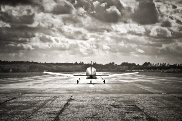 sepia toned light aircraft take-off into dark clouds