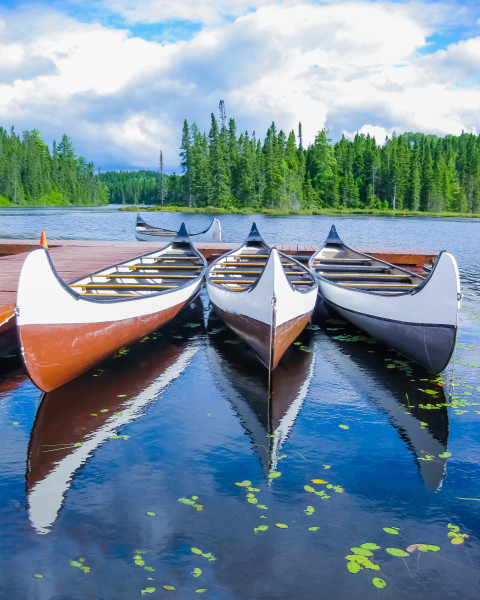 Canoes reflected on a turquoise lake, Quebec, Canada