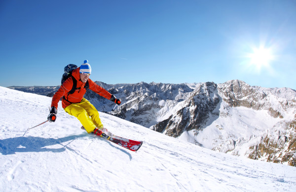 Skier skiing downhill in high mountains against sunset