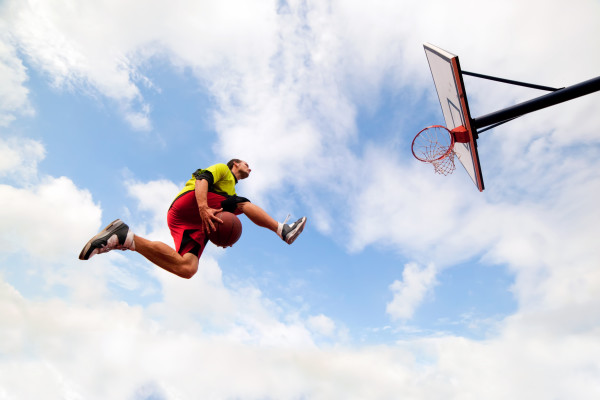 Young man making a slam dunk playing streetball basketball