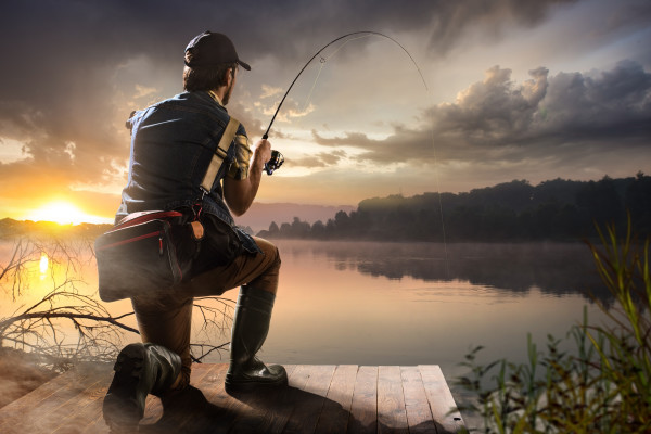 Young man fishing at misty sunrise