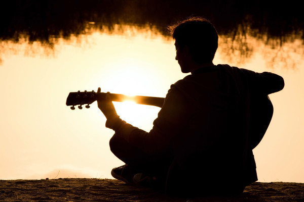 silhouette of a young man on the beach with a guitar