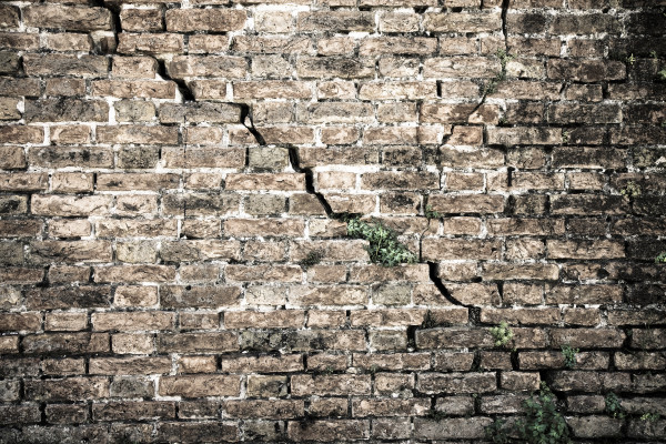 Cracked brick wall – Deep crack in a brick wall – toned image