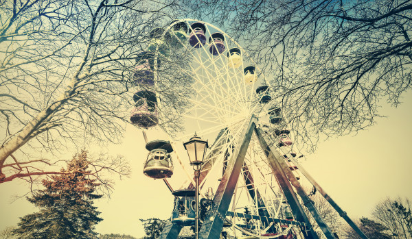Retro old film faded picture of ferris wheel in a park.