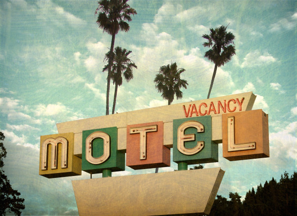 ged and worn vintage photo of retro motel sign with palm trees