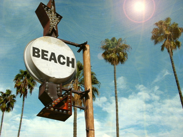 aged and worn vintage photo of beach sign with palm trees