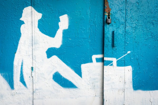 Moscow, Russia – September 27, 2015: a blue and white silhoette of a painted person on the garage wall. Tourist listening to the radio and drinking.