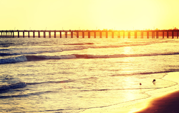 Vintage toned wooden pier on beach at sunset, California, USA