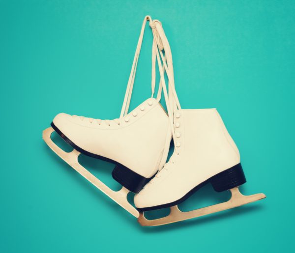 white ice skates for figure skating, hanging on a blue backgroun